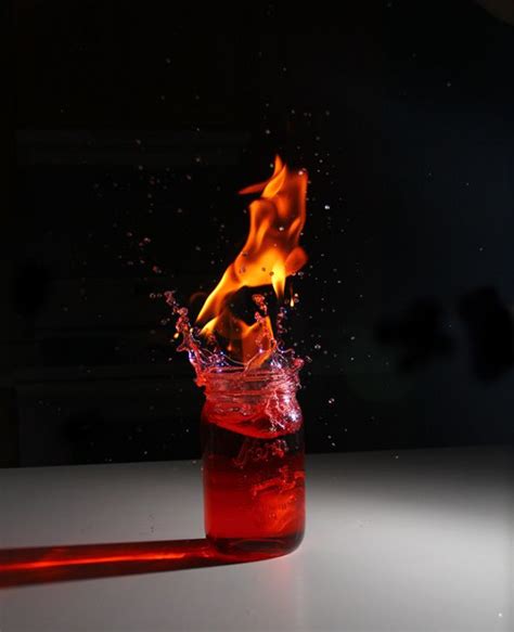 A Glass Filled With Liquid And Fire On Top Of A Table