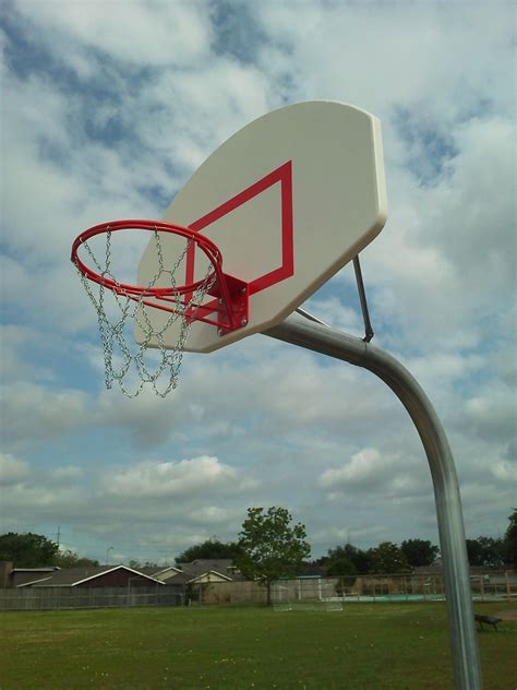 A Basketball Hoop With Chains Hanging From Its Side In A Park Setting