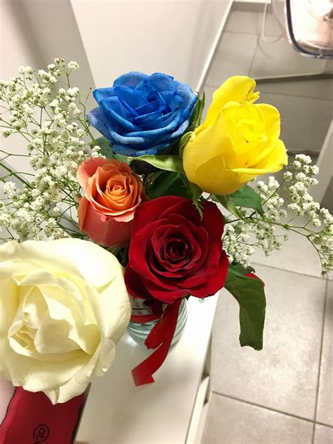 A Vase Filled With Different Colored Roses On Top Of A Counter Next To A Mirror