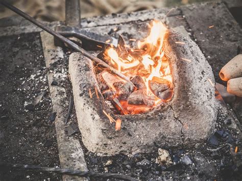 The Blacksmith Holds The Billet Over Hot Coals In A Clay Oven