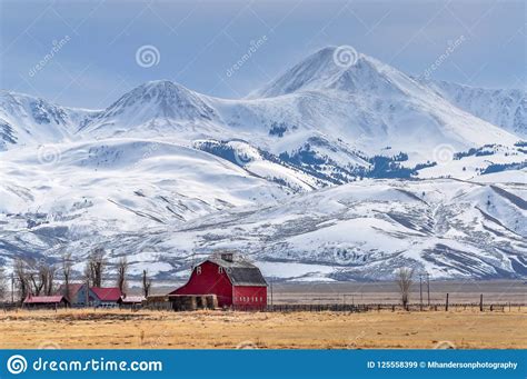 Towering Snow Covered Mountains Above A Small Farm In Montana Editorial