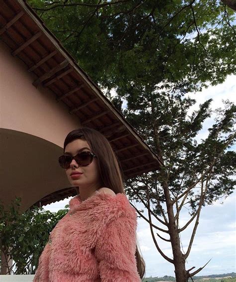 A Woman Wearing Sunglasses And A Pink Fur Coat