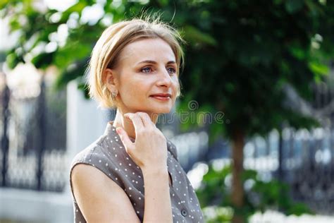 Portrait Of Thoughtful 40 Years Old Woman Standing Outdoors Among Green