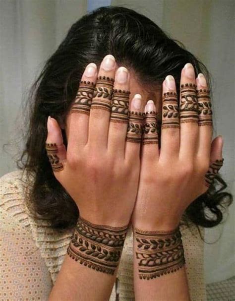 A Woman Holding Her Hands To Her Face With Henna Tattoos On Its Arms