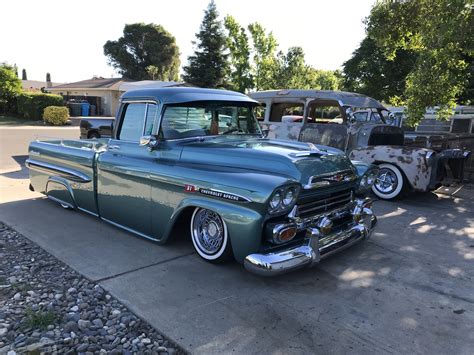 Two Old Trucks Parked Next To Each Other In A Driveway