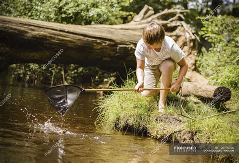Boy Kneeling By River Bank — Bending Over Exploration Stock Photo