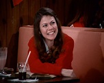 a woman sitting at a table smiling for the camera