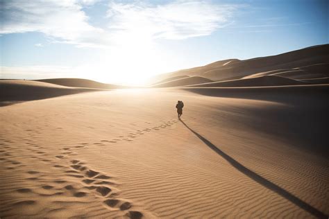 A Person Walking Through The Sand Leaving Footprints On The Dunes At