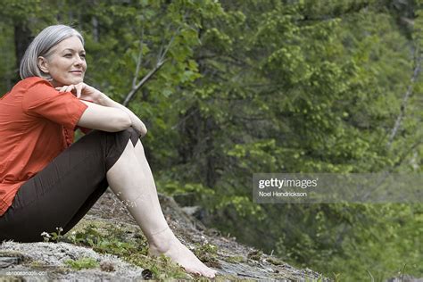 Mature Woman Sitting On Rock In Forest Photo Getty Images
