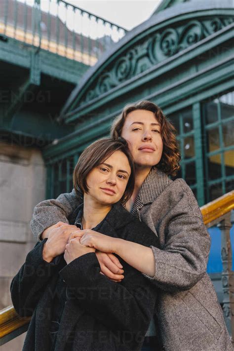 Portrait Of Lesbian Couple Embracing On Staircase In City Stock Photo