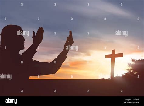 Silhouette Man Raising Hand While Praying To Jesus On Sunset Background