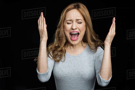 Young Beautiful Woman Screaming In Exasperate Isolated On Black Stock