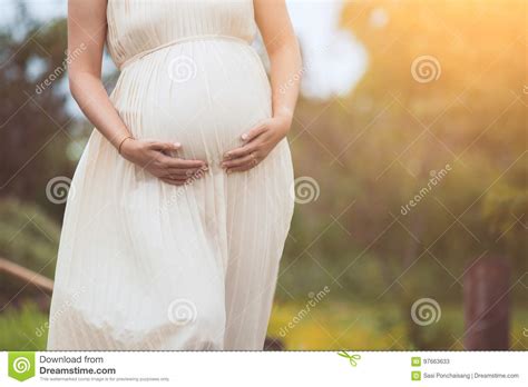 Pregnant Woman Touching Her Big Belly And Walking In The Park Stock