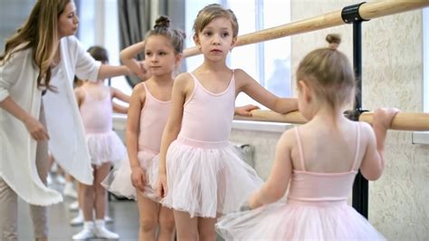 Young Female Ballet Teacher Showing Little Girls How To Hold Ballet