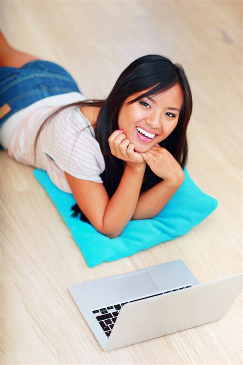 Portrait Of Young Beautiful Asian Woman Lying On The Floor With Laptop