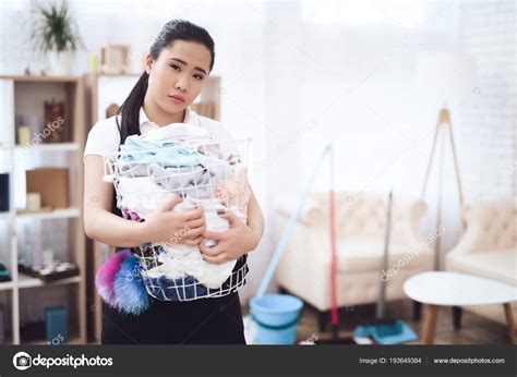 frustrado empregada asiática coletando roupas sujas cesta lavanderia quarto fotos imagens de
