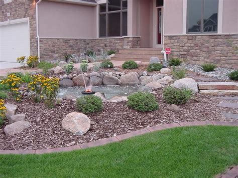 A House With Rocks And Flowers In The Front Yard