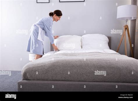 Smiling Female Housekeeper Making Bed In Hotel Room Stock Photo Alamy