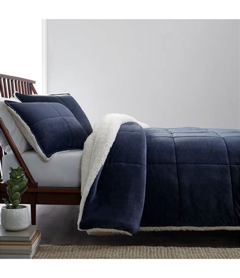 A Bed With A Blue Comforter And White Pillows