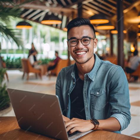 Premium Ai Image A Man Sitting At A Table With A Laptop And Smiling