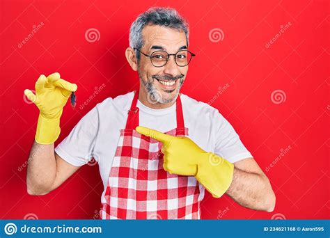 handsome middle age man with grey hair wearing apron and holding cockroach smiling happy