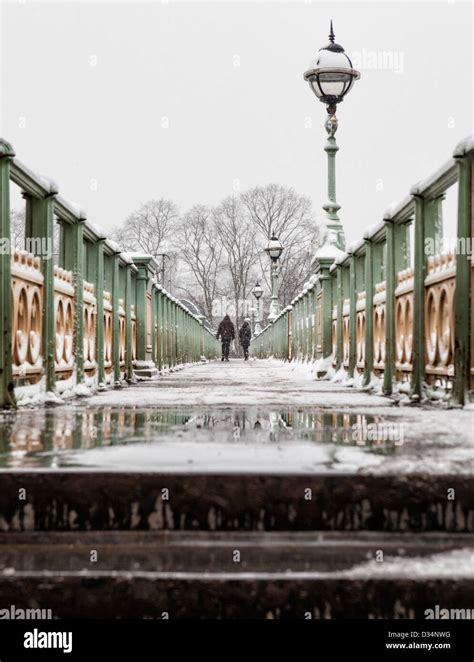 Two People Walking Across Snow Covered Pedestrian Bridge At Richmond