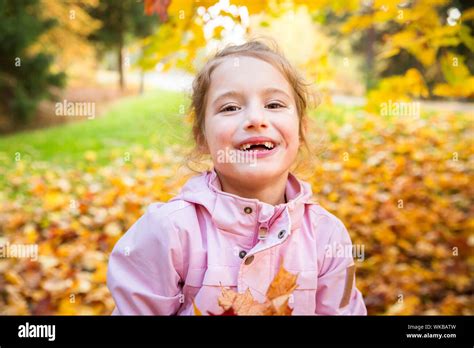 Portrait Of Cute Little Girl With Missing Teeth Playing With Yellow