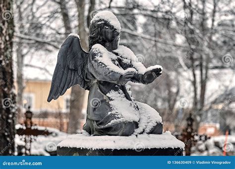 Frozen Angel Covered With Snow At The Cemetery Grave Yard In Winter