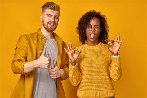 excited beautiful mixed race couple shows thumb up gesture agree to do something and collaborate