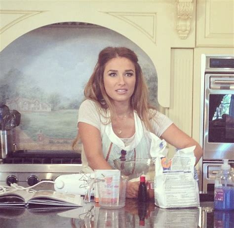 A Woman Sitting At A Kitchen Counter In Front Of An Oven With Bottles And Containers On It