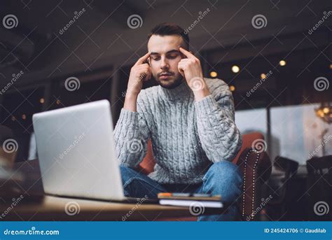 Baffled Man Rubbing Temples While Doing Job From Home Stock Photo