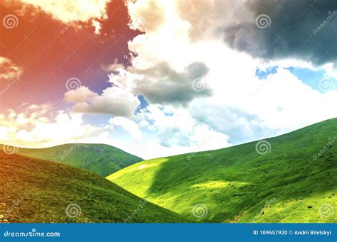 Hills With Green Grass And Blue Sky With White Puffy Clouds Stock Photo