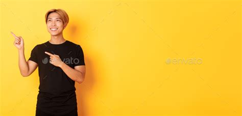 Portrait Of Handsome Korean Blond Guy Pointing Fingers Upper Left