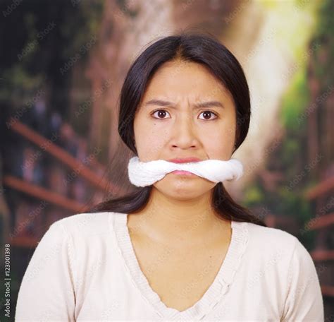 Young Brunette Woman Wearing White Sweater Gagged With Rope Facing Camera Hostage Concept