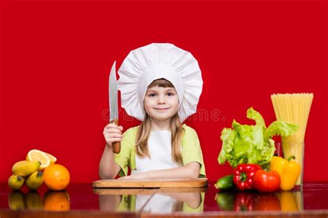 Happy Little Girl In Chef Uniform Cuts Vegetables In Kitchen Stock