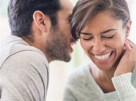 A Man And Woman Smiling At Each Other With Their Hands On Their Chins As They Look Into One