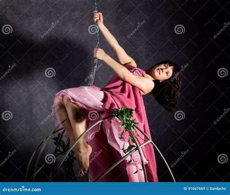 Elegance Girl In A Pink Skirt Swinging On A Metal Swing Holding On To Chains Stock Image