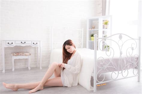 A Woman Sitting On The Floor Next To A White Bed