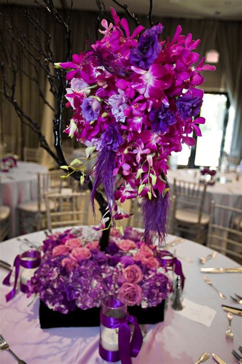 Purple And White Flowers Are Arranged In A Centerpiece On A Table With
