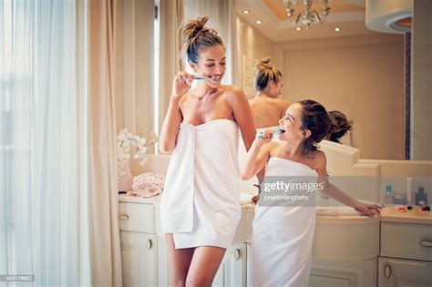 Mother And Daughter Are Brushing Their Teeth In The Bathroom High Res