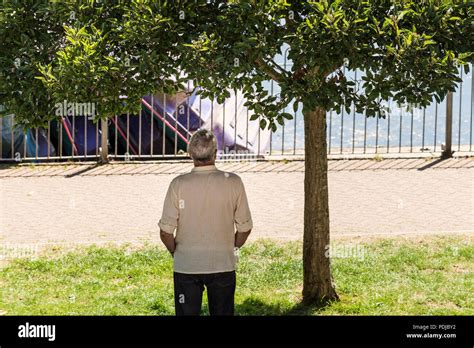 A Man Standing In The Shade Under A Tree In Trenance Park In Newquay