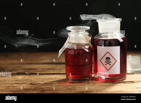 Glass Bottles Of Poison With Warning Signs On Wooden Table Space For