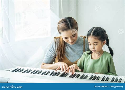 Pequeña Y Feliz Hija Asiática Tocando El Piano Con Su Madre En Casa