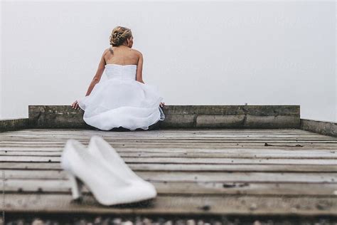 Bride Sitting On A Jetty And Blurred High Heels In The Front By Stocksy Contributor Akela