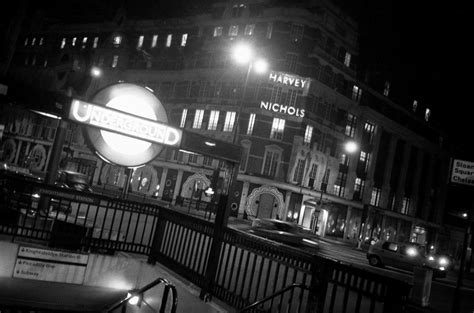 A Black And White Photo Of A London Underground Entrance With Cars