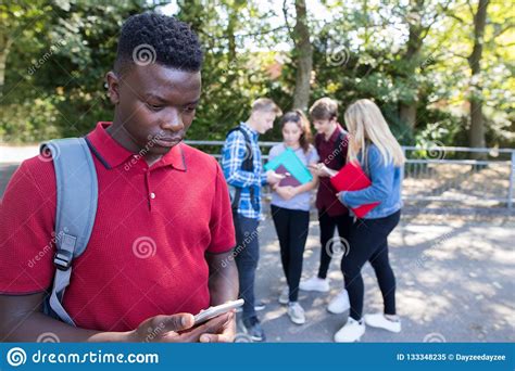 Unhappy Teenage Boy Being Bullied By Text Message At School Stock Image