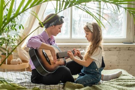Mamá E Hija En El Sofá Tocando La Guitarra Una Mujer Y Una Niña
