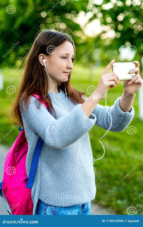 Beautiful Schoolgirl Girl Teenager Summer In Nature In His Hands Holds A Smartphone Behind His