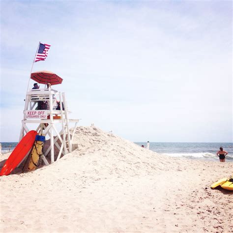 A Lifeguard Tower On The Beach With Surfboards And Kayaks In The Sand
