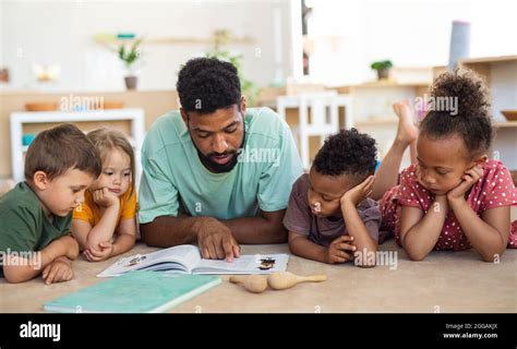 Group Of Small Nursery School Children With Man Teacher On Floor